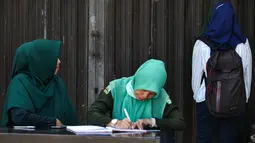 Polisi syariah menasehati seorang wanita (kanan) yang terjaring razia busana muslim di sepanjang jalan Lambaro, provinsi Aceh, Selasa (23/7/2019). Aceh merupakan satu-satunya provinsi di Indonesia yang memberlakukan hukum Syariat Islam bagi warganya. (Photo by CHAIDEER MAHYUDDIN / AFP)