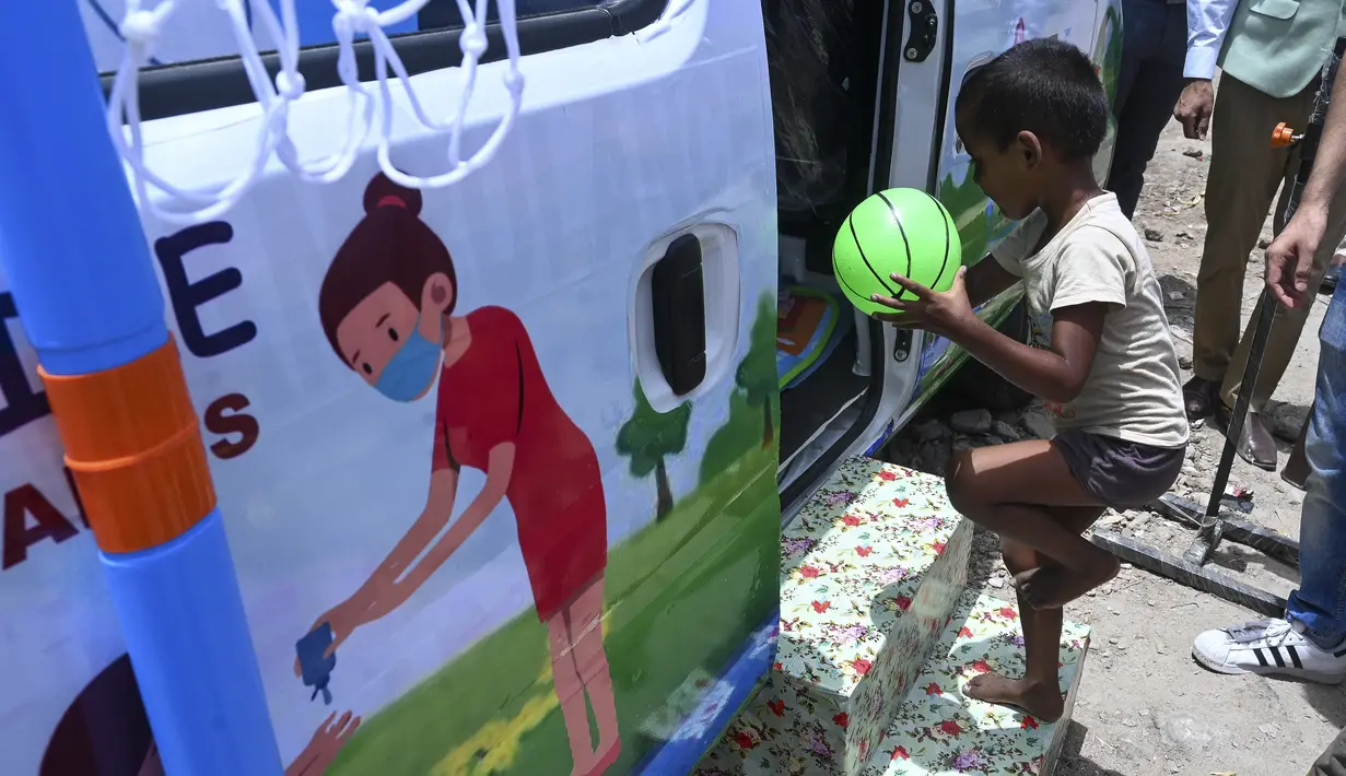 Seorang anak laki-laki membawa bola memasuki sebuah van, yang diluncurkan oleh Polisi Delhi bekerja sama dengan laboratorium Star Imaging and Path, untuk memberikan sampel usap untuk menguji virus corona Covid-19 di New Delhi, India (1/7/2021).  (AFP/Prakash Singh)