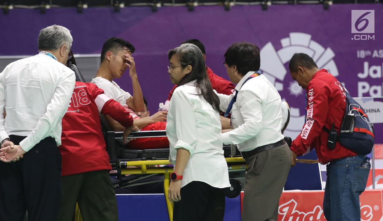 Tunggal putra Indonesia, Anthony Sinisuka Ginting dibawa dengan tandu ketika kondisi kakinya sakit saat melawan China, Shi Yuqi pada final Bulutangkis Beregu Putra Asian Games 2018 di Jakarta, Rabu (22/8).  (Liputan6.com/Helmi Fithriansyah)