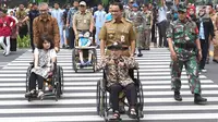 Gubernur DKI Jakarta Anies Baswedan mendorong penyandang disabilitas berkursi roda saat meresmikan pelican crossing di Halte Transjakarta Bank Indonesia (BI), Jakarta, Selasa (4/9). (Liputan6.com/Immanuel Antonius)