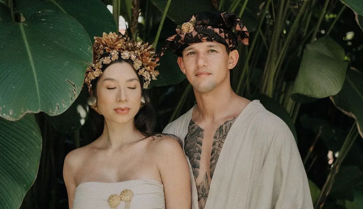 Lihat gaya memesona luar biasa dari pasangan Irfan dan Jennifer Bachdim mengenakan baju adat Bali. Tampil bak penganting, Jennifer mengenakan atasan berupa kemben, dipadu dengan kain yang diberi tambahan detail belt emas dan bros, serta hiasan kepala, anting, dan gelang yang serasi. Sedangkan Irfan tampil memamerkan dadanya dengan atasan serupa kimono dan kain bawahan yang warna serasi dengan yang dikenakan Jennifer, semakin menyerupai orang lokal dengan udeng dan keris yang dipegangnya. Foto: Instagram.