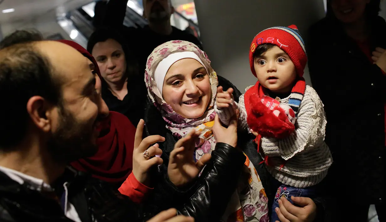 Pengungsi asal Suriah Baraa Haj Khalaf menggendong seorang anak saat tiba di bandara Internasional O'Hare, AS, Rabu (7/2). Baraa dan keluarganya harus menjalani introgasi panjang agar bisa melewati otoritas bandara. (AFP Photo/ Scott Olson)