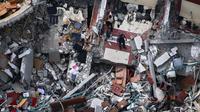 Warga Palestina memeriksa bangunan hancur yang menampung kantor The Associated Press dan media lainnya, setelah terkena serangan udara Israel pekan lalu, di Kota Gaza, Jumat (21/5/2021). Israel dan Hamas telah sepakat untuk gencatan senjata setelah 11 hari pertempuran. (AP Photo/Hatem Moussa)