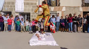 Pria berkostum setan melompati bayi-bayi yang diletakkan di atas matras selama tradisi El Salto del Colacho di desa Castrillo de Murcia, Spanyol, Minggu (3/6). Festival melompati bayi ini sudah menjadi perayaan tahunan sejak 1620 (afp/CESAR MANSO)