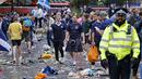 Penggemar Skotlandia berjalan di antara sampah yang ditinggalkan oleh penggemar yang berpesta sebelum pertandingan grup D kejuaraan sepak bola Euro 2020 antara Inggris dan Skotlandia, di London, Jumat (18/6/2021).  (AFP/Tolga Akmen)