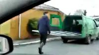 Karena tidak ingin barang bawaan dalam mobil van jatuh ke jalan, seorang pria membantu temannya berlari di belakang van untuk memegangi.