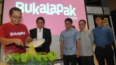 CEO dan founder Bukalapak Achmad Zaky (kiri) memotong tumpeng disaksikan Menkominfo Rudiantara (kedua kiri) saat perayaan ulang tahun yang ke-6 serta peresmian kantor baru mereka di kawasan Kemang, Jakarta, Selasa (12/1). (Liputan6.com/Faisal R Syam)