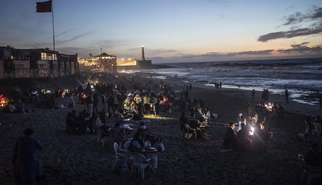 <p>Orang-orang berbuka puasa di tepi pantai di Rabat, Maroko, Sabtu (23/4/2022). Untuk pertama kalinya dalam dua tahun sejak pandemi COVID-19, orang-orang dapat menghidupkan kembali tradisi Ramadhan dengan berkumpul dan berbuka puasa di tempat umum. (AP Photo/Mosa'ab Elshamy)</p>