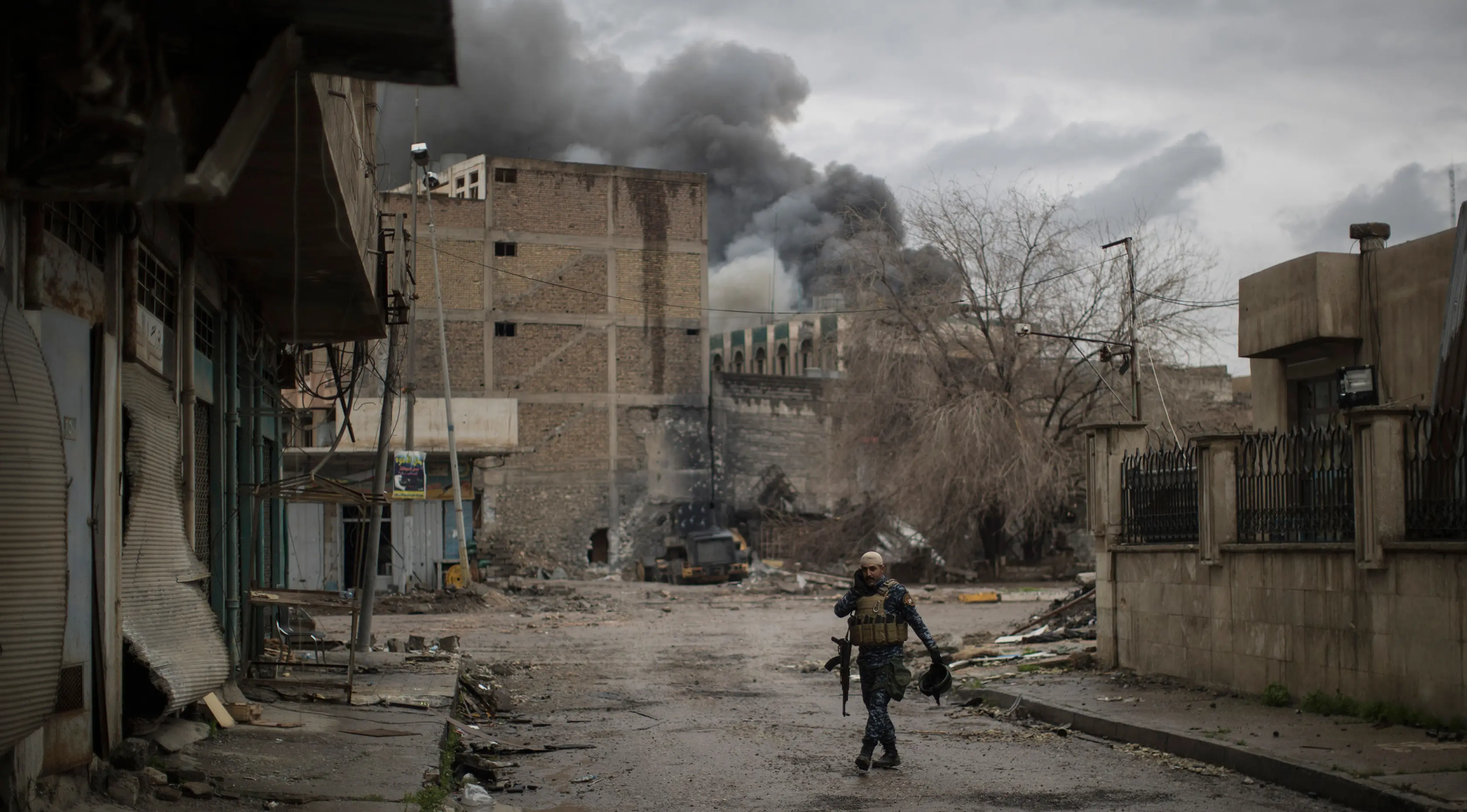 Polisi Irak berjalan sambil berbicara dengan rekannya menggunakan radio saat bertempur melawan militan ISIS di barat Mosul, Irak, 16 Maret 2017. (AP Photo/Felipe Dana)