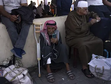 Warga Palestina menunggu untuk menyeberang ke Mesir di perbatasan Rafah di Jalur Gaza, pada Senin, 16 Oktober 2023. (AP Photo/Fatima Shbair)