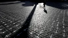 Seorang perempuan melintasi Alun-alun Kota Tua di Praha di mana ribuan salib dilukis untuk menandai satu tahun sejak kematian pertama akibat Covid-19 di Republik Ceko, Senin (22/3/2021). Sekelompok aktivis melukis salib untuk mengkritik tanggapan pemerintah terhadap pandemi. (AP/Petr David Josek)