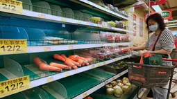 Seorang perempuan membeli makanan di supermarket untuk persiapan menghadapi Badai Tropis Kompasu di Hong Kong pada Selasa (12/10/2021). Observatorium Hong Kong mengeluarkan sinyal nomor 8, level tertinggi ketiga dalam skalanya, saat siklon tropis Kompasu semakin mendekati kota. (AP Photo/Vincent Yu)