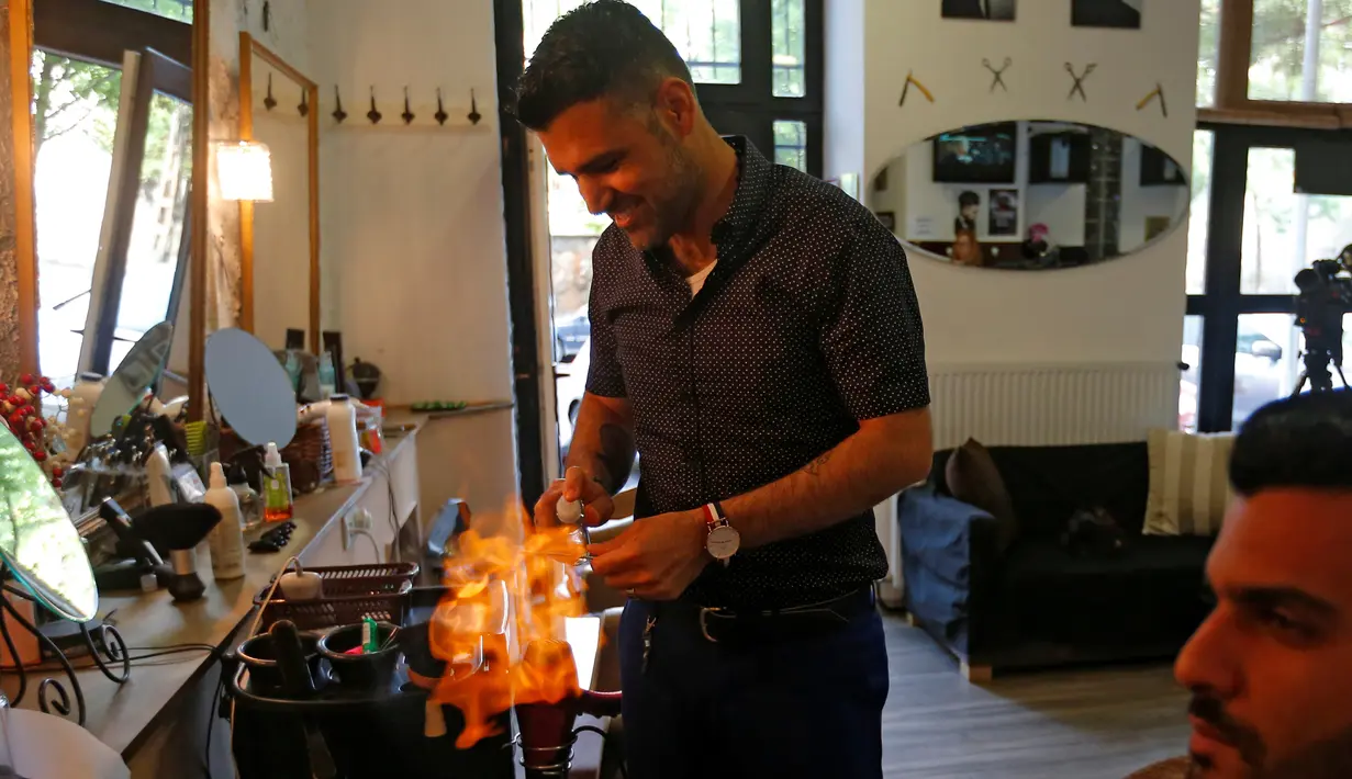 Ibrahim Haji Mohammad, seorang pengungsi Kurdi dari Suriah saat melayani pengunjung di toko cukur miliknya di Budapest, Hongaria, 24 Mei 2016. (REUTERS / Laszlo Balogh)
