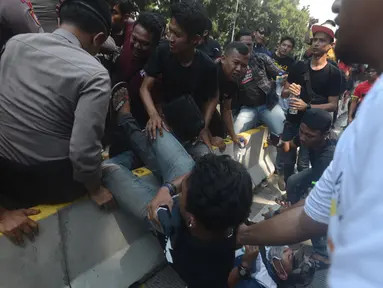 Dua orang pria terjatuh saat terjadi aksi saling dorong antara polisi dan massa driver taksi online yang tergabung dalam Aliando di Jalan Medan Merdeka Barat, Jakarta, Rabu (28/3). (Merdeka.com/Imam Buhori)