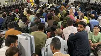 Orang-orang Afghanistan duduk di dalam pesawat militer AS untuk meninggalkan Afghanistan, di bandara militer di Kabul, Kamis (19/8/2021). Ribuan orang berlomba-lomba melarikan diri dari Afghanistan setelah pasukan Taliban berhasil merebut pemerintahan negara itu. (Shakib RAHMANI/AFP)