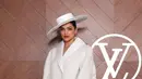 Deepika Padukone mengenakan coat putih senada dengan topi nya dipadukan stocking hitam serasi dengan gloves leather, heels, dan tasnya. [dok. Louis Vuitton]