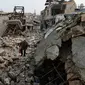 Seorang warga berjalan diantara puing-puing bangunan yang hancur di kawasan Allepo Timur, Suriah (20/1). Aleppo kini dikuasai penuh oleh pemerintah, setelah jatuh ke tangan pemberontak, pada Juli 2012. (AP/Hassan Ammar)