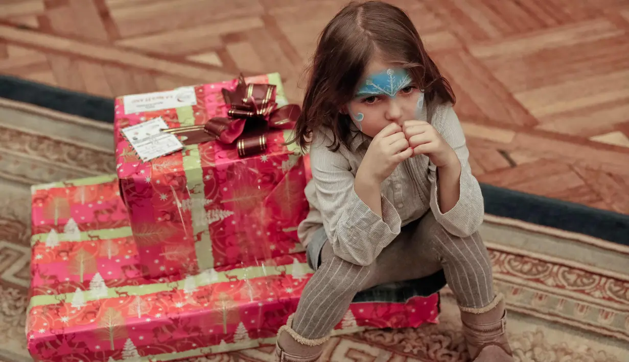 Seorang gadis duduk di atas hadiahnya saat pertunjukan Natal untuk anak-anak keluarga militer di Bucharest, Rumania, (21/12). (AP Photo/Vadim Ghirda)