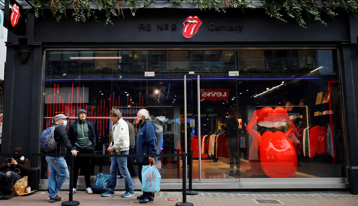 Orang-orang mengantre untuk memasuki toko andalan The Rolling Stones yang baru sebelum hari pertama pembukaannya di London, Rabu (9/9/2020). Rolling Stones membuka membuka toko pertamanya di 9 Carnaby Street. (Tolga Akmen / AFP)