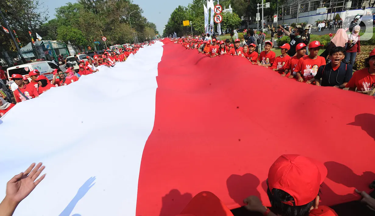 Relawan Jokowi-Ma'ruf Amin membawa bendera raksasa sepanjang sekitar 200 meter saat menyambut pelantikan Presiden-Wapres terpilih periode 2019-2024 di sekitar Patung Kuda, Jakarta, Minggu (20/10/2019). (merdeka.com/Arie Basuki)
