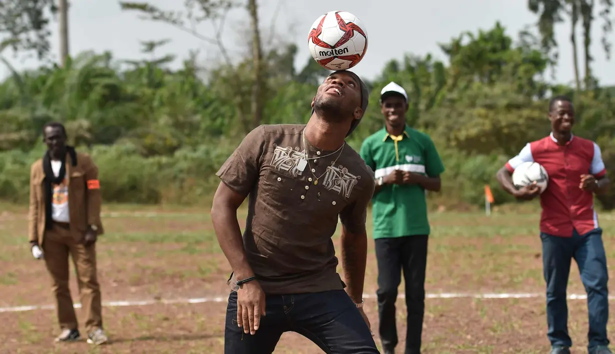 Mantan penyerang Chelsea, Didier Drogba berusaha mengontrol bola saat bermain dengan murid-murid saat peresmian sekolah di Pokou-Kouamekro, dekat Gagnoa, Pantai Gading tengah barat (17/1). (AFP Photo/Sia Kambou)