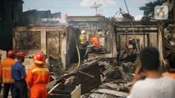 Petugas berusaha memadamkan sisa api yang membakar toko dan pemukiman warga di kawasan Manggarai, Jakarta, Selasa (7/7/2020). Tidak ada korban jiwa dalam peristiwa itu, namun akibat kebakaran sebanyak 40 bangunan yang didominasi toko mebel ludes terbakar. (Liputan6.com/Immanuel Antonius)