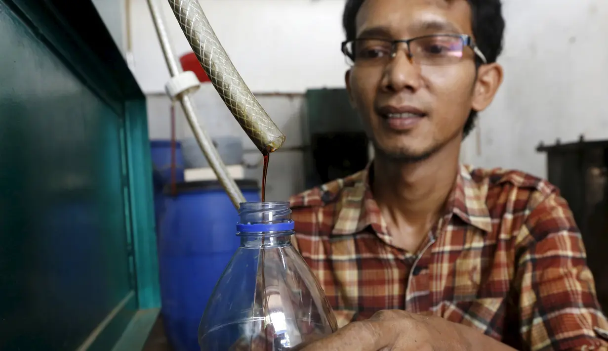 Hamidi saat menampung cairan hasil dari olahan pembakaran sampah plastik di bengkel kerjanya dekat TPA Rawa Kucing, Tangerang, (17/3). Dengan hasil temuannya ini, Hamidi dapat membuat bahan bakar yang hemat energi. (REUTERS / Beawiharta)
