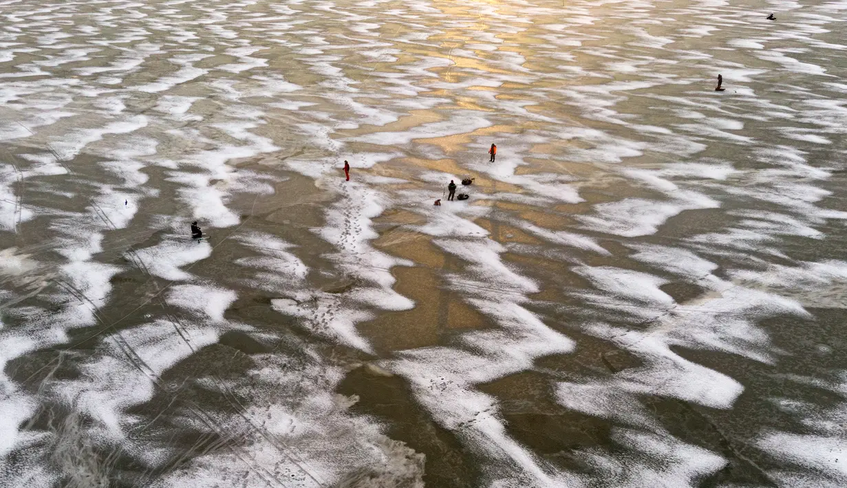 Pandangan udara menunjukkan para pria sedang memancing di tengah Laut Bothnia yang membeku di dekat Vaasa, Finlandia, 28 Desember 2018. Memancing di laut beku merupakan hal yang ditunggu-tunggu oleh sebagian warga setempat. (OLIVIER MORIN / AFP)