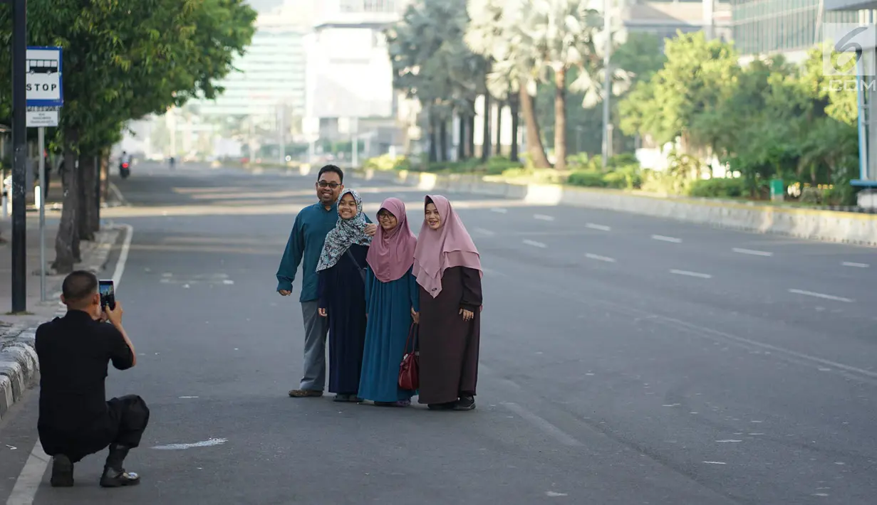Warga berfoto di tengah Jalan MH Thamrin, Jakarta, Rabu (5/6/2019). Banyaknya warga Ibu Kota yang mudik ke kampung halaman untuk merayakan Hari Raya Idul Fitri membuat jalan protokol terpantau lengang. (Liputan6.com/Immanuel Antonius)