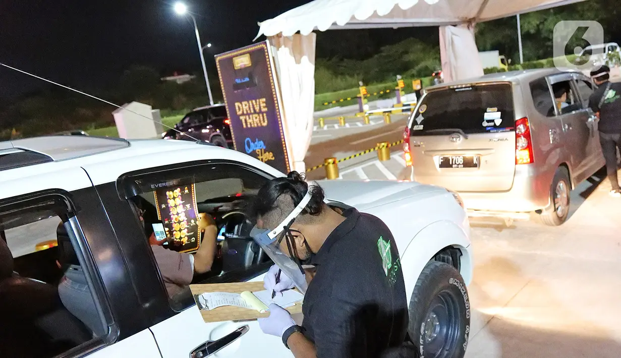Pegawai mencatat pesanan makanan penonton yang akan menyaksikan pemutaran film secara drive-in di Cikarang, Bekasi, Jawa Barat, Rabu (3/6/2020). Kehadiran drive-in cinema memberikan hiburan alternatif kepada warga di tengah pandemi virus corona COVID-19. (Liputan6.com/Herman Zakharia)