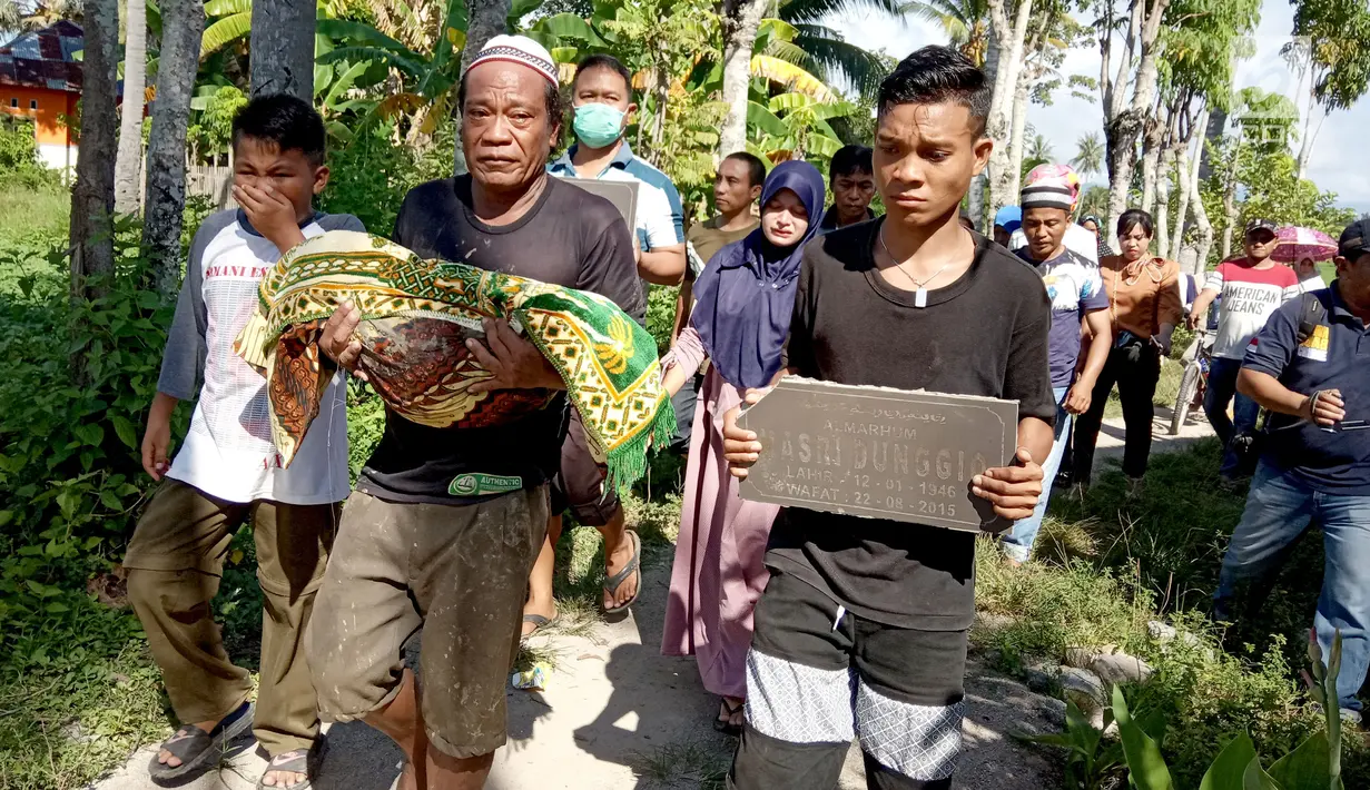 Warga memindahkan jasad dari kuburan di Desa Toto Selatan, Kabupaten Bone Bolango, Gorontalo, Sabtu (12/1). Pemindahan dilakukan akibat adanya perbedaan dalam keluarga terkait pemilihan calon legislatif (caleg). (Liputan6.com/Arfandi Ibrahim)