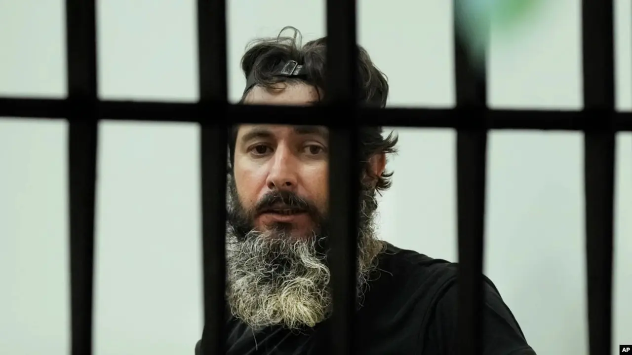 Bassam al-Sheikh Hussein (42), melihat melalui jendela bank, di Beirut, Lebanon, Kamis, 11 Agustus 2022. (AP/Hussein Malla)