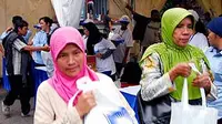 Dua perempuan membawa bingkisan sembako gratis yang dibagikan dalam rangka HUT ke-12 PAN (Partai Amanat Nasional) di Parkir Selatan Senayan, Jakarta.(Antara)