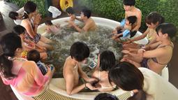 Petugas memberikan cokelat kepada pengunjung saat mandi spa cokelat di Hakone, Jepang, Senin (13/2). Mandi spa cokelat ini digelar setiap tahun bulan Februari. (AFP PHOTO / Kazuhiro Nogi)