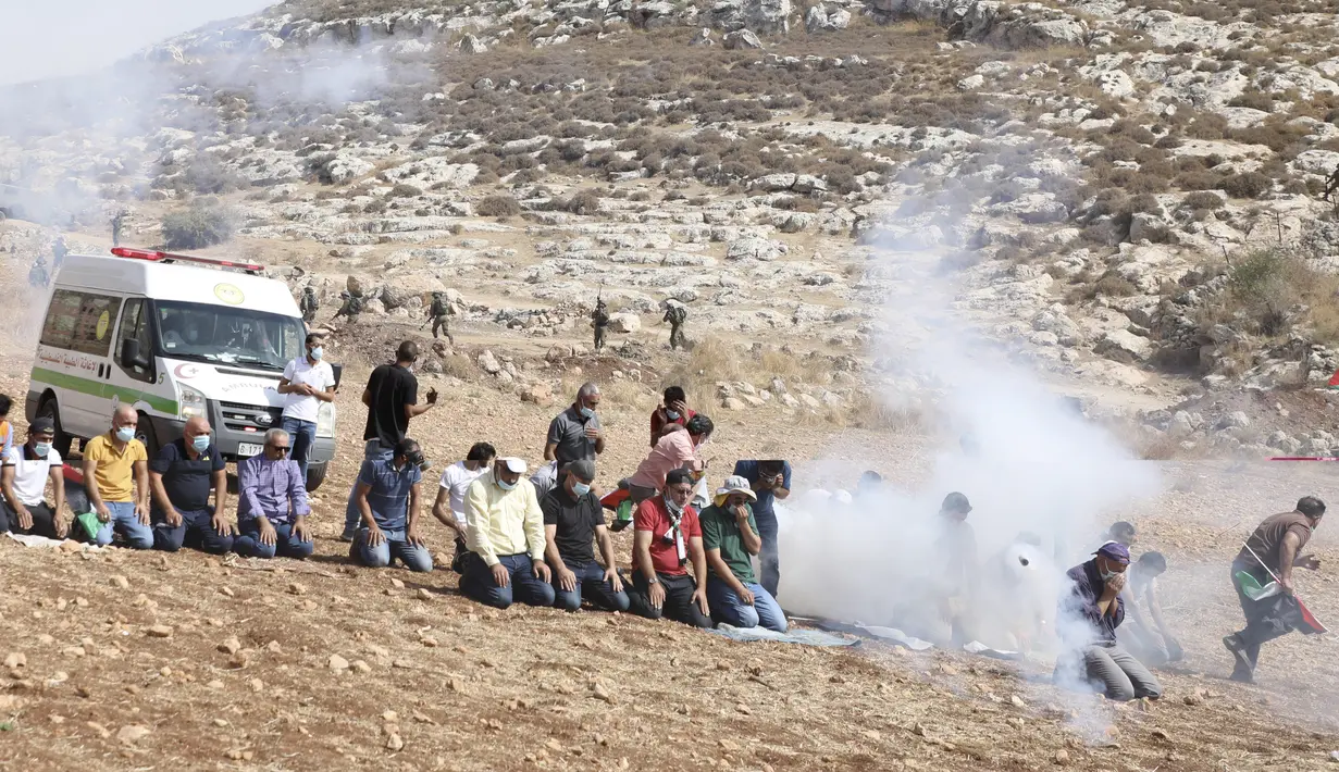 Pengunjuk rasa Palestina melaksanakan salat di tengah tembakan gas air mata oleh tentara Israel di dekat desa Beit Dajan, timur Nablus, Palestina (9/10/2020). (AFP/Jaafar Ashtiyeh)