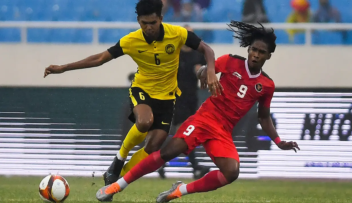 <p>Penyerang Timnas Indonesia U-23, Ronaldo Joybera R Junior berebut bola dengan bek Malaysia, Muhammad Azam bin Azmi Murad dalam pertandingan perebutan medali perunggu SEA Games 2021 di Stadion My Dinh, Minggu (22/5/2022). Indonesia ditahan imbang 1-1 dan menang 4-3 di adu penalti. (AFP/Ye Aung Thu)</p>