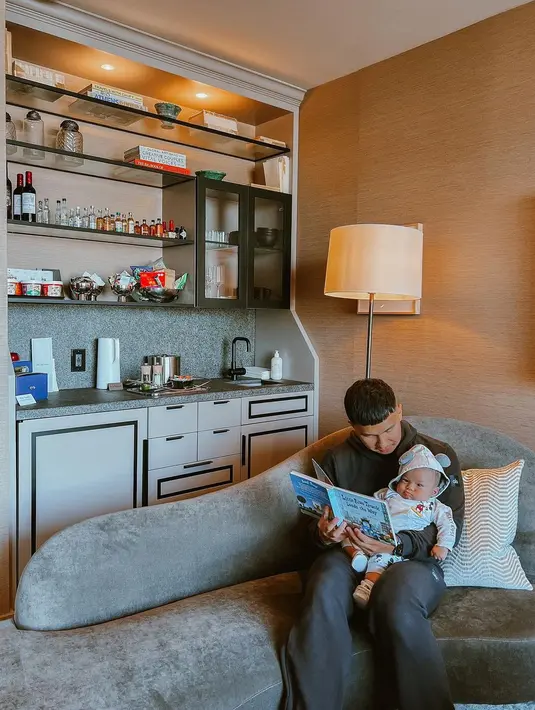 Nikita Willy mengunggah empat foto. Pertama, menampilkan Indra Priawan memangku baby Issa, duduk di sofa, bersandar pada bantal dengan motif garis lengkung berurutan. Ia membuka majalah seolah mengajak si kecil belajar baca. Momen ayah dan anak ini memenangkan hati warganet. Hampir 200 ribu orang mengirim tanda suka. (Foto: Dok. Instagram @nikitawillyofficial94)