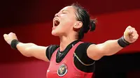 Lifter Indonesia Windy Cantika Aisah meluapkan kegembiraan saat bertanding pada cabang angkat besi 49kg putri Olimpiade Tokyo 2020 di Tokyo International Forum, Sabtu, 24 Juli 2021. (Vincenzo PINTO / AFP)