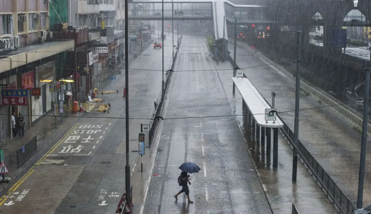 Seorang pria berjalan di tengah hujan yang disebabkan Topan Kalmaegi di kawasan Sheung Wan, Hong Kong, (16/9/2014). (AFP PHOTO/Xaume Olleros)