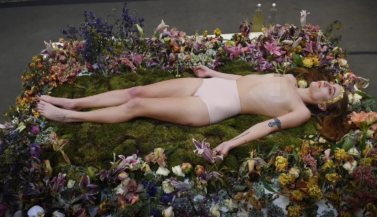 Millie Brown, seorang seniman wanita dalam posisi tidur di atas karya seninya saat pameran berjudul 'Wilting Point' atau Titik Layu di LA Art Show, Los Angeles, Minggu (31/1). Brown akan bertahan selama 5 hari hanya meminum air. (Mark Ralston/AFP)