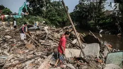 Sejumlah warga mengumpulkan kayu bekas sisa penertiban bangunan di bantaran Sungai Ciliwung, kawasan Bukit Duri, Jakarta Selatan, Selasa (11/7). Terdapat 355 bangunan yang ditertibkan guna menanggulangi banjir di Jakarta ini (Liputan6.com/Faizal Fanani)
