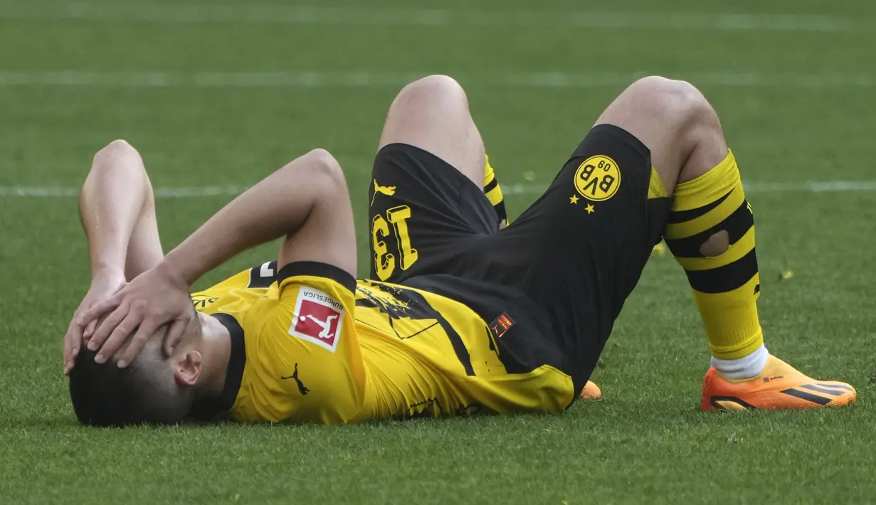 Bek Borussia Dortmund, Rapahel Guerreiro berbaring sambil menutupi wajahnya setelah berakhirnya laga menghadapi FSV Mainz pada laga pekan terakhir Liga Jerman 2022/2023 di Dortmund, Jerman (27/5/2023). Ditahan imbang FSV Mainz 2-2, Borussia Dortmund harus merelakan gelar juara Liga Jerman 2022/2023 menjadi milik Bayern Munchen. (AP Photo/Michael Probst)