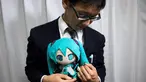 Akihiko Kondo asal Jepang berpose dengan boneka aktris virtual, Hatsune Miku sambil mengenakan cincin kawin mereka di Tokyo, 10 November 2018. Pria berusia 35 tahun itu memutuskan menikah dengan boneka anime pada 4 November lalu. (Behrouz MEHRI/AFP)