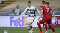 Kapten Timnas Portugal, Cristiano Ronaldo, saat coba melewati kawalan pemain Serbia pada laga kedua Grup A kualifikasi Piala Dunia 2022 di Stadion Rajko Mitic, Minggu (28/3/2021) dini hari WIB. (Pedja Milosavljevic/AFP)