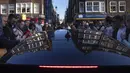 Sebuah taksi bergerak melewati kerumunan warga yang bersuka ria merayakan Hari Raja di pusat Kota Amsterdam, Belanda, Selasa (27/4/2021). Pihak berwenang mendesak warga untuk tetap berpegang pada peraturan jarak sosial COVID-19. (AP Photo/Peter Dejong)