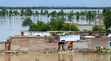 Orang-orang berdiri di rumah mereka yang terendam banjir setelah hujan lebat di distrik Nowshera, Provinsi Khyber-Pakhtunkhwa, Pakistan pada tanggal 16 April 2024. (Abdul MAJEED/AFP)