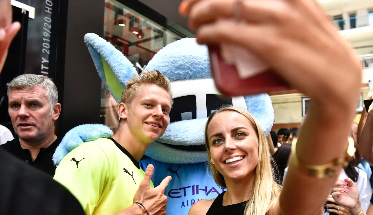 Penggemar wanita berselfie dengan pemain Manchester City  Oleksandr Zinchenko selama acara promosi di Hong Kong (23/7/2019). The Citizens akan menghadapi Kitchee SC dalam laga uji cobadi Hong Kong Stadium pada 24 Juli 2019. (AFP Photo/Anthony Wallace)