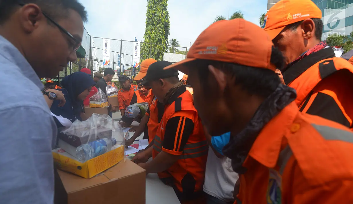 Petugas Penangganan Prasarana dan Saran Umum (PSSU) atau pasukan oranye mendapatkan sembako gratis di Jakarta, Jumat (3/8). Pembagian sembako gratis tersebut dalam rangka menyambut HUT ASABRI ke-47 tahun. (Merdeka.com/Imam Buhori)