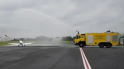 Sebuah truk pemadam kebakaran menyemprotkan pesawat Shark Ultralight milik Pilot Belgia-Inggris Zara Rutherford sebelum lepas landas di lapangan terbang Kortrijk-Wevelgem di Wevelgem, Belgia, Rabu (18/8/2021). (AP Photo/Virginia Mayo)