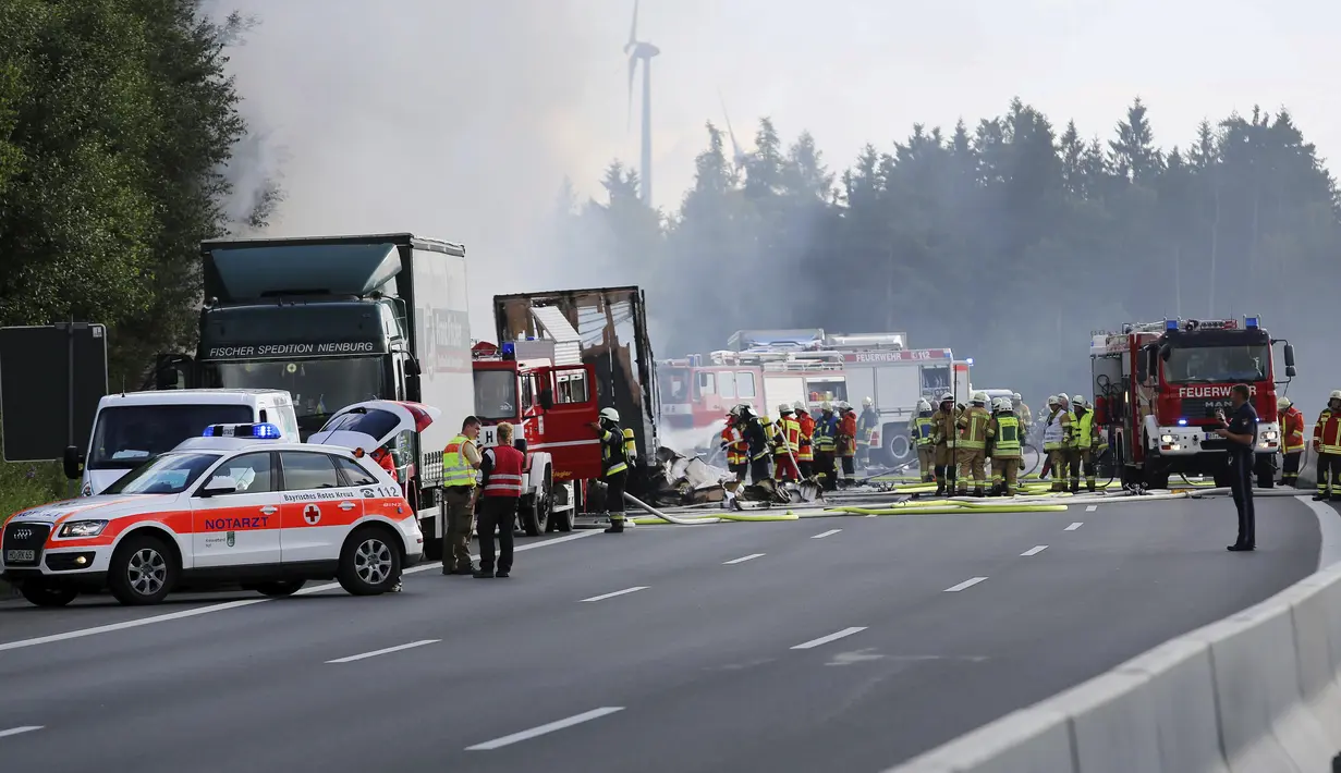 Petugas penyelamat berada di lokasi kecelakaan di Muenchberg, Jerman, Senin (3/7). Sebuah bus wisata menabrak sebuah truk dan terbakar. (AP Photo)